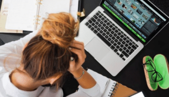 Woman with hands on head looking at laptop.