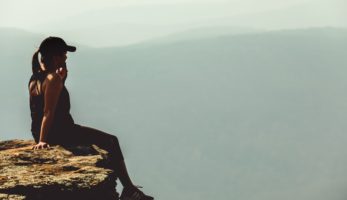 Hiker sitting on cliff looking into the distance.