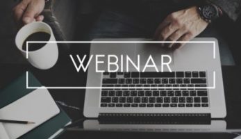 A laptop and coffee mug with the word "Webinar" over it.