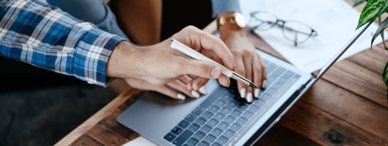 A photo of a pair of hands typic on a laptop keyboard.