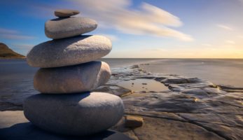 An image of rocks on a sandy beach, depicting calmness and wellbeing