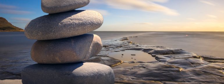 An image of rocks on a sandy beach, depicting calmness and wellbeing