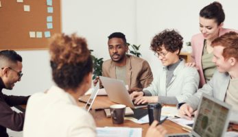 images of a group of employees gather together at a table working on benefits.