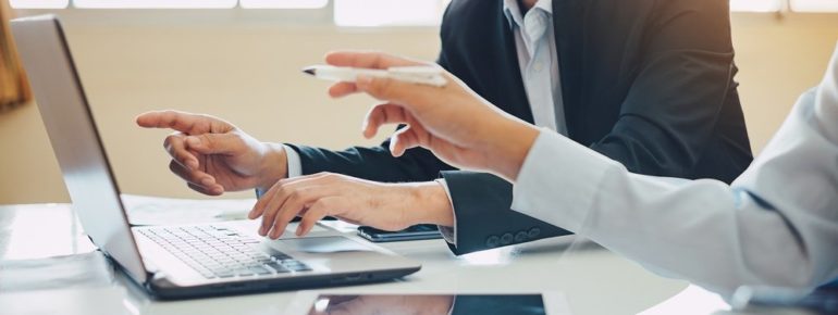 image: Two individuals pointing at something on a laptop screen and discussing