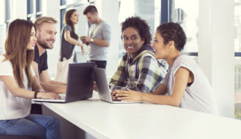 image: group of individuals sitting at a table, typing on their computers