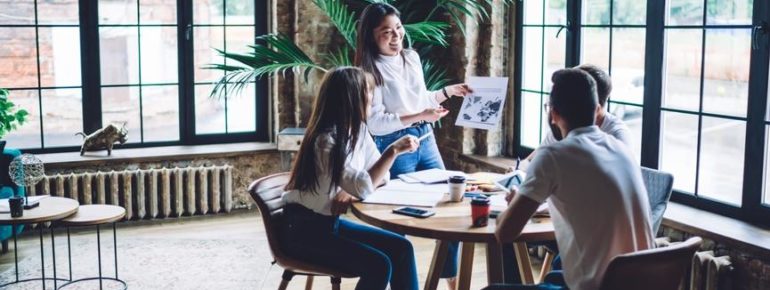 image: Woman laughing as she presents a document to her team