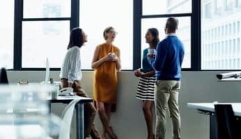 An image of four individuals standing by a wall and chatting