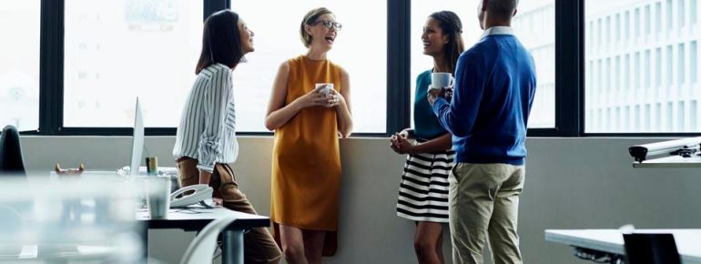 An image of four individuals standing by a wall and chatting