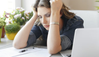 an image of a woman holding her head, eyes closed, from fatigue