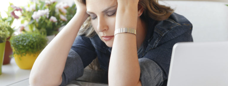 an image of a woman holding her head, eyes closed, from fatigue