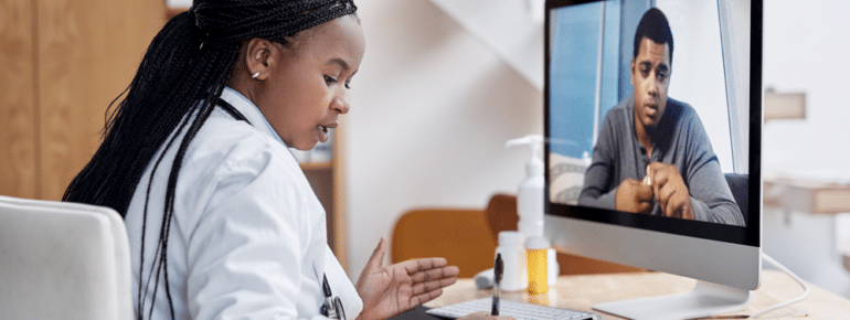 image: Doctor taking notes while speaking to a patient via telehealth