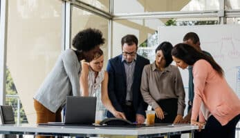 Image of a group of people huddled together looking at something on a table.