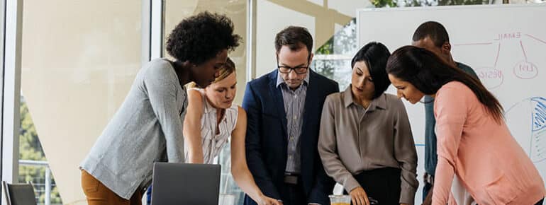 Image of a group of people huddled together looking at something on a table.