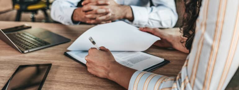 A photo of two pair of hands working at a desk as two people discuss employee benefits.