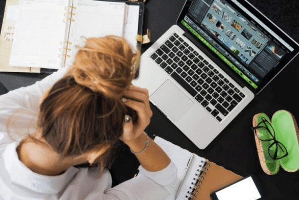 Woman with hands on head looking at laptop.