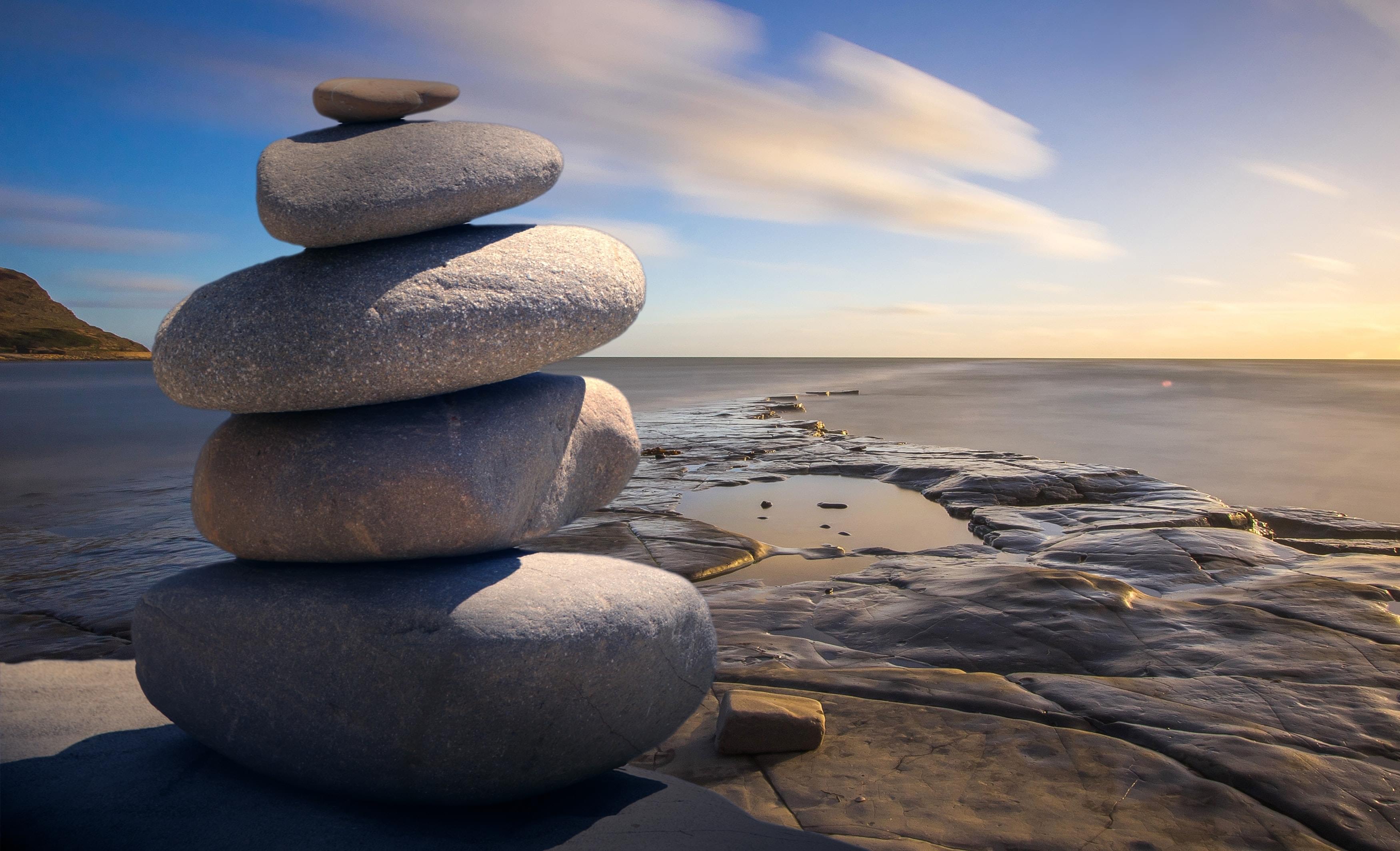 An image of rocks on a sandy beach, depicting calmness and wellbeing
